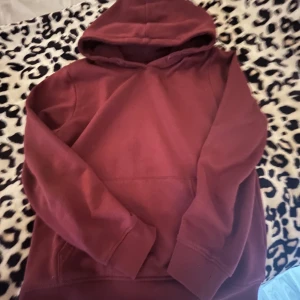 Vinröd hoodie - Säljer en mysig vinröd hoodie med långa ärmar och en praktisk magficka. Perfekt för kyliga dagar och avslappnade stunder. Passar bra till jeans eller leggings.