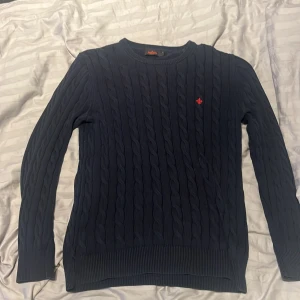 Svart stickad tröja från Morris - Säljer en stilren stickad tröja från Morris med kabelstickat mönster. Tröjan har långa ärmar och en liten röd logga på bröstet. Inga täcken på slitage. Sitter som S-M. Skriv och fråga om det är något!