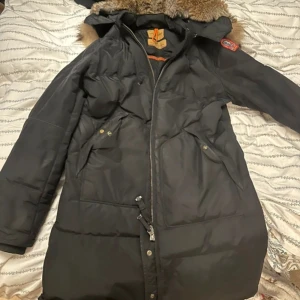 Svart dunjacka från Parajumpers - Säljer en svart dunjacka från Parajumpers med pälsdetaljer på huvan. Jackan har en dragkedja framtill och flera praktiska fickor. Perfekt för kalla vinterdagar. 🖤