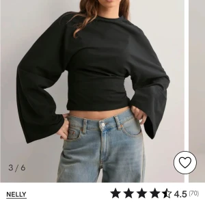 Svart topp med vida ärmar från Nelly - Säljer en stilren svart topp från Nelly med vida långa ärmar. Toppen har en tight passform och är perfekt för en trendig look. Den är tillverkad i ett mjukt material som ger en bekväm känsla. Passar utmärkt till både jeans och kjol. Aldrig använd🩷