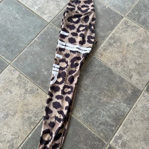 Aim’n tights Small - Snygga leopardmönstrade leggings med vita ränder. Perfekta för en trendig look, dessa leggings är både bekväma och stiliga. Passar utmärkt för vardagsbruk eller till träning
