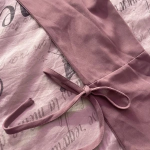 Ljuslila blus med knytband - Säljer en ljuslila blus med v-ringning och långa ärmar. Blusen har knytband vid ärmarna och en lös passform som ger en avslappnad look. Perfekt för en stilren och bekväm outfit.