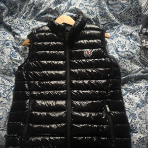 Svart Moncler väst - Säljer äkta Moncler väst då den inte längre används. Skicket är 7/10, Inga defekter men den är använd därför priset. Tveka inte på att höra av er vid frågor