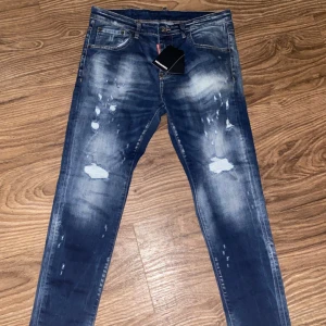Blå jeans från Dsquared2 - Snygga blå jeans från Dsquared2 med en cool slitningseffekt och ljusa partier. De har en klassisk femficksdesign och en knappgylf. Perfekta för en trendig look. Dom är aldrig använda.  Storlek 48