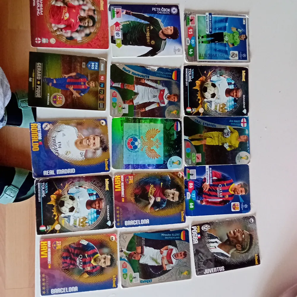 En samling av fotbollskort med olika spelare från lag som Real Madrid, Barcelona, Juventus och Chelsea. Kort med spelare i olika matchställ och positioner. Perfekt för samlare eller fotbollsfans som vill utöka sin kollektion.. Asusteet.