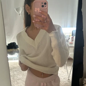 Vit ribbad tröja - Säljer en stilren vit ribbad tröja med v-ringning. Tröjan har en croppad passform och långa ärmar, perfekt för en avslappnad look. Passar bra till både jeans och kjol. Perfekt för kyligare dagar!