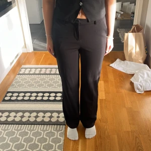 Svarta straight byxor från Vero Moda - Svarta byxor från Vero Moda i klassisk straight modell med normal passform. Byxorna har hög midja och är tillverkade i ett mjukt material som känns skönt mot huden. Perfekta till en snygg topp eller skjorta för en clean look.