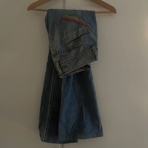 Lågmidjade bootcut jeans med vit söm och färgglada fickor - Jätte snygga lowww rise bootcut jeans. Skriv för mått och bilder på!