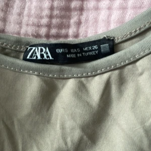 Beige ärmlös linnetopp från Zara - Snygg beige linnetopp från Zara med rund halsringning och ärmlös design. Perfekt att styla med jeans eller kjol för en clean och enkel look. Mjuk och lätt bomullskänsla som gör den skön att bära hela dagen.