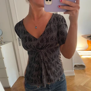 Gråmönstrad omlottopp med v-ringning - Säljer en grå topp med svart leopardmönster och snygg omlottdetalj framtill!