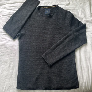  långärmad tröja Lindbergh - En stilren svart långärmad tröja från Lindbergh. Tröjan har en diskret struktur i tyget och rund halsringning. Perfekt för dig som gillar en clean och enkel look. Materialet känns mjukt och passar bra till lager-på-lager.