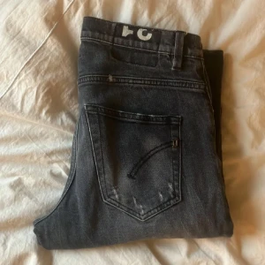 Svarta jeans från Dondup, stl 31 - Snygga svarta jeans från Dondup i klassisk femficksmodell. Jeansen har en lätt tvättad look med diskreta slitningar. Längd från midjan och ner till fot är 92 cm