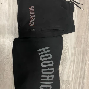 Svarta mjukisbyxor från Hoodrich - Bra skick väldigt billig byte funkar Svarta mjukisbyxor från Hoodrich med stor logga tryckt längs benet och mindre logga vid fickan. Byxorna har dragsko i midjan och är tillverkade i mjukt material som passar perfekt för chill eller streetwear. Snygg och enkel design med bekväm passform.