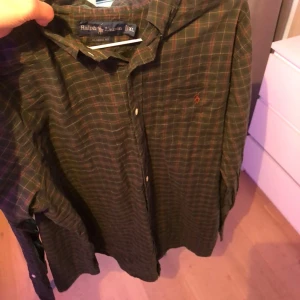 Grön rutig skjorta från Ralph Lauren - Snygg grön rutig skjorta från Ralph Lauren i klassisk passform. Skjortan har knappar framtill, lång ärm och den ikoniska broderade loggan på bröstet. Perfekt för dig som gillar en avslappnad men stilren look.