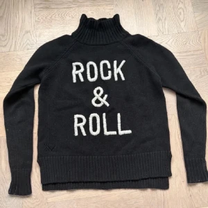 Svart polotröja Zadig & Voltaire - Snygg polotröja från Zadig & Voltaire i 65% ull storlek 12-xs, tröjan är i väldigt fint skick, finns lite små fläckar som inte syns alls skriv för mer bilder. Ny pris i butik ca 2000-3000kr.