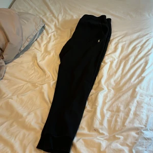 Svarta mjukisbyxor från Polo Ralph Lauren - Svarta mjukisbyxor från Polo Ralph Lauren med klassisk broderad logga på låret. Byxorna har dragsko i midjan och muddar vid bensluten. Perfekta för chill eller träning, tillverkade i mjukt bomullsmaterial.