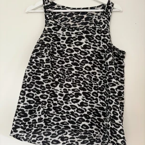 Leopardmönstrad linnetopp  - ärmlös linnetopp i svartvitt leopardmönster. Toppen har en avslappnad passform och rund halsringning, perfekt för att sticka ut med en edgy vibe. Tunt och lätt material som känns skönt mot huden. Strl s använd enstaka gång 