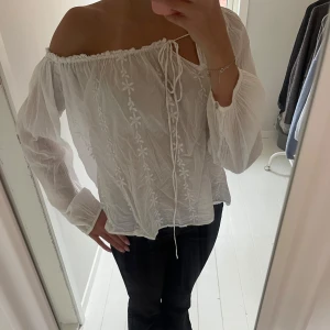 Offshoulder blus med blommor - En super fin blus i storlek xs . Modellen är offshoulder och går att dra åt med snören. Den är broderad men fina blommor på.