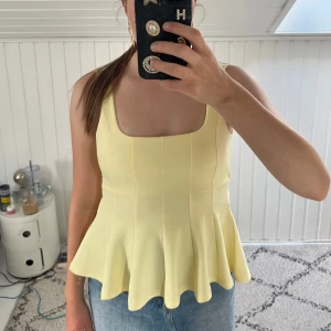 Gul top med rosett i ryggen - Superfin ljusgul top med breda axelband och fyrkantig ringning. Toppen har öppen rygg med snygg knytrosett och är tillverkad i ett mjukt, stretchigt material. Perfekt för sommarens alla tillfällen och lätt att styla med jeans eller kjol. Pris kan diskuteras!