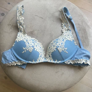 Blå spetsbh med blommigt mönster intimissimi  - Supersöt blå BH från intimissimi med krämvit spets och blommigt broderi. Kuporna är vadderade. En liten maska har gått upp (se sista bilden) i övrigt är den i iprincip nytt skick 