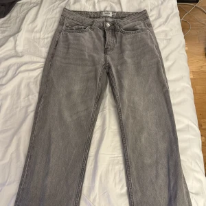 Grå jeans från lager 157 Icon - Snygga grå jeans från lager 157 Icon med klassisk femficksdesign och raka ben. Jeansen har en enkel look med silverfärgade knappar och bälteshällor. Perfekta för dig som gillar en stilren och avslappnad vibe.