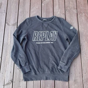 Svart sweatshirt från Replay - Säljer en svart sweatshirt från Replay med stort tryck på bröstet och texten 'Denim Goods Since 1981'. Tröjan har rund hals, långa ärmar och ribbade muddar vid ärmslut och nederkant. Perfekt för en chill och avslappnad stil.