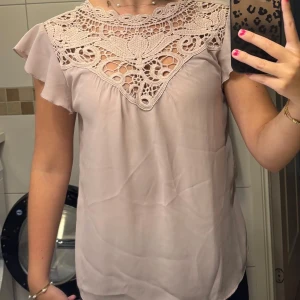 Ljusrosa blus med spets från ONLY - Supersöt ljusrosa blus från ONLY med vacker spets upptill och volangärmar. Blusen är ärmlös med en flowy passform och har ett fint, detaljerat mönster över bröstet🫶🏻Storlek 36