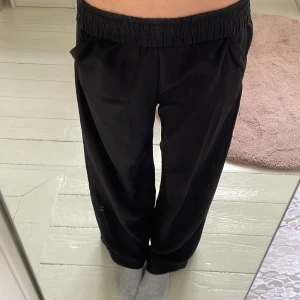 Svarta vida byxor med resårmidja - Säljer ett par svarta byxor med bred resår i midjan och raka, vida ben. Byxorna har fickor i sidorna och är riktigt sköna och avslappnade. Perfekta för dig som gillar en loose fit och enkel stil.