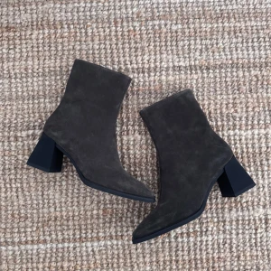 Vagabond Hedda brun mocka  - Snygga mörkbruna boots i mocka med fyrkantig tå och bred klack. Skorna har dragkedja på insidan och en stilren, minimalistisk design som passar till många outfits. Så snygga med långa byxor där framdelen av skon sticker fram. Helt oanvända, i samma skick som i butik. Denna färg finns inte längre att få tag på och köptes i Vagabond butik för 1700kr. 