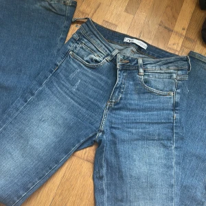 Blå jeans från Zara - Säljer ett par snygga blå jeans från Zara. De har en klassisk femficksdesign med dragkedja och knapp framtill. Jeansen har en lätt slitning för en trendig look. Perfekta för en avslappnad stil. Byxor är jätte lågmidiadde