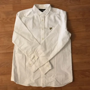 Vit skjorta från Lyle & Scott - Säljer en stilren vit skjorta från Lyle & Scott med klassisk krage och knappar framtill. Skjortan har ett broderat emblem på bröstet och långa ärmar. Perfekt för en elegant look. Skick 9/10 och nästan som ny. Storlek M men passar S. Skriv vid frågor 😉