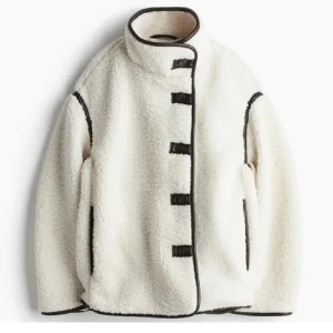 Teddyjacka med knappar - Säljer en mysig vit teddyjacka med svarta detaljer/knappar. Passar perfekt nu till våren. Lite smink fläckar längst upp men inget man riktigt ser. Helt slut i alla storlekar! Hör av dig vid frågor🥰