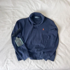 Blå tröja från Polo Ralph Lauren - Ralph Lauren Button up – Klassisk kabelstickad tröja i 100% bomull. Perfekt för en tidlös och stilren look. Diskret broderad logga på bröstet. Mjuk, bekväm och i fint skick. Passar både till vardags och mer uppklädda tillfällen.  ✔️ Skickas samma dag eller senast nästa! ✔️ Mätningar finns i bilderna.  Hör av dig vid frågor! 