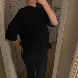Svart tröja med trekvartsärm - Säljer en stilren svart tröja med trekvartsärm. Tröjan har knappar i ryggen och en normal passform. Perfekt för en minimalistisk look.