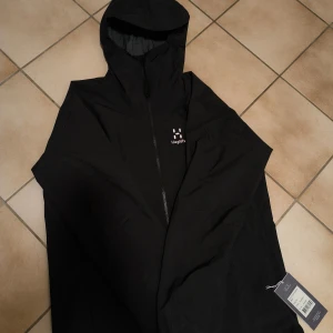 Svart regnjacka från Haglöfs - https://www.intersport.se/klader/jackor/skaljackor/haglofs-chaos-gore-tex-m-skaljacka-herr/tarn-blue-solid