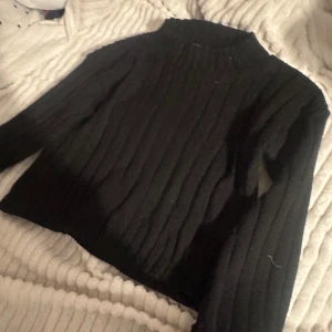 Svart ribbad tröja från booboo - Säljer en svart ribbad magtröja med långa ärmar. Från Boohoo. Perfekt för kyligare dagar och enkel att matcha med olika outfits. Hör av dig vid intresse!