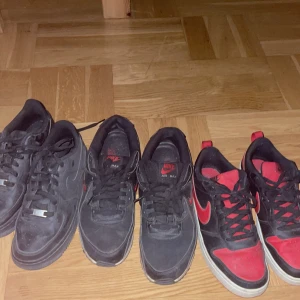 Svarta och röda Nike sneakers - Säljer tre par Nike sneakers. Två par är svarta med röda detaljer och ett par är helsvarta. Skorna har snörning och är perfekta för vardagsbruk. De röda och svarta skorna har en iögonfallande röd sula. En är storlek 38 ett annat par är 39 och en är storlek 42. Priset på skorna diskuteras.