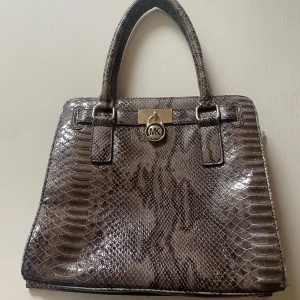  Michael Kors ormskinnsmönstrad handväska - Snygg handväska i ormskinnsmönster. Jag vet inte om den är äkta eller fejk då jag har fått den💕 OBS! Tror inte att den är äkta men vet inte och en av dragkedjorna på insidan av väskan går inte att stänga. 🐆🪩🎱