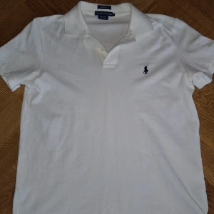 Vit Ralph Lauren piké - Säljer en klassisk vit pikétröja från Ralph Lauren i 100% bomull. Tröjan har en broderad logotyp i mörkblått på bröstet.       Tröjan sitter skönt och mjukt.                             Pris kan självklart diskuteras 