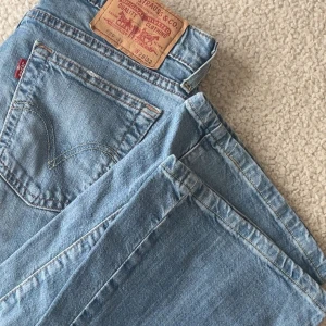 Levis 529 jeans i ljusblå denim - Snygga Levis 529 jeans i ljusblå denim. Klassisk femficksdesign med knappgylf och den ikoniska Levis-lappen på baksidan. Perfekta för en avslappnad stil.