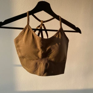 Tränings BH/topp - Säljer en snygg grön sporttopp/BH med ribbad nederdel och smala axelband som korsas i ryggen💚