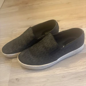 Michael kors sneakers - Snygga svarta loafers med diskret mönster och vit sula. Perfekta för en stilren look. Lätta att ta på och av.