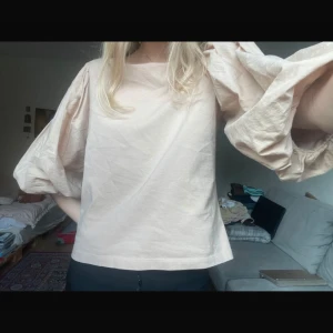 Beige blus med puffärmar - Säljer en stilren beige blus med stora puffärmar. Perfekt för att ge en trendig touch till din outfit. Blusen har en enkel design med rund hals och är tillverkad i ett lätt material.