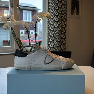 Vita sneakers från Philippe Model - Snygga vita sneakers från Philippe Model med svarta detaljer. Skorna har en klassisk design med snörning och en diskret logotyp på sidan. Perfekta för en stilren look. Använda cirka 5 gånger ( nyskick) köpta för 3500. Vid minsta lilla fundering är de bara att skriva så svara jag så snabbt jag kan mvh Hugo 😄