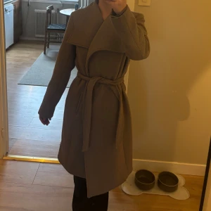 Beige kappa med knytband - Beige kappa med knytband i midjan, från ellos. Älskar denna kappa, men den kommer tyvärr inte till användning längre. Nypris 1000kr