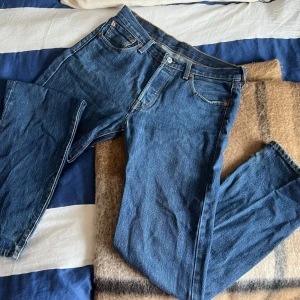 Blå jeans från Levi's - Säljer ett par klassiska blå Levi's 501 jeans. De har en rak passform och är tillverkade i slitstarkt denim. Perfekta för en avslappnad stil. Midjan är hög och de har den ikoniska Levi's-lappen på baksidan. Storleken är 30 32