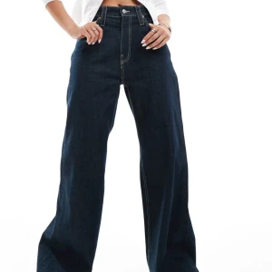 Mörkblå vida jeans - Snygga mörkblå jeans från weekday med låg midja och vida ben. Den har perfekta djupa och stora fickor bakifrån och framifrån. har används några gånger och är lite trasiga vid benen men är allmänt fortfarande i bra kvalitet.