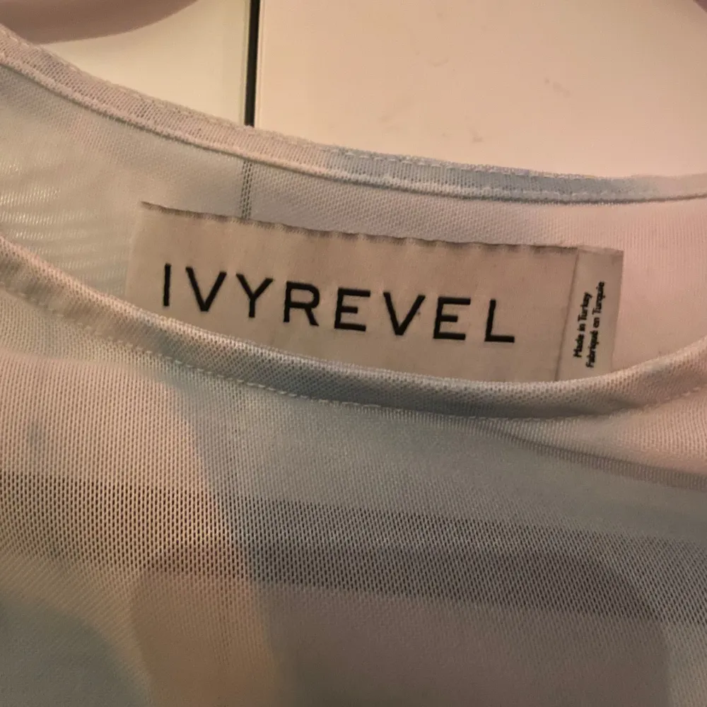 Säljer en snygg blå och vit mesh topp från Ivyrevel. Toppen har ett molnliknande mönster och långa ärmar. Perfekt för att lägga till en cool touch till din outfit. Tillverkad i polyester och elastan för en bekväm passform.. Yläosat.