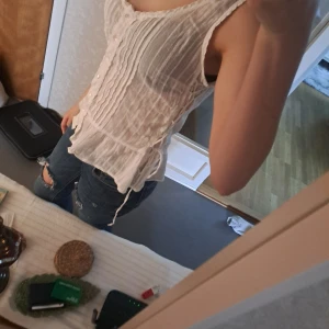 Vit ärmlös blus - Säljer en söt vit ärmlös blus med knappar framtill. Blusen har en lätt och luftig design med volangdetaljer som ger en romantisk känsla. Perfekt för varma sommardagar eller som ett lager under en kavaj.