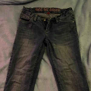 Jeans från EDC by Esprit - Snygga blå jeans från EDC by Esprit med klassisk femficksdesign och broderade detaljer på bakfickorna. De har en knappgylf och bälteshällor, vilket gör dem perfekta för en avslappnad stil. Jeansen har en lätt slitning pga användning.